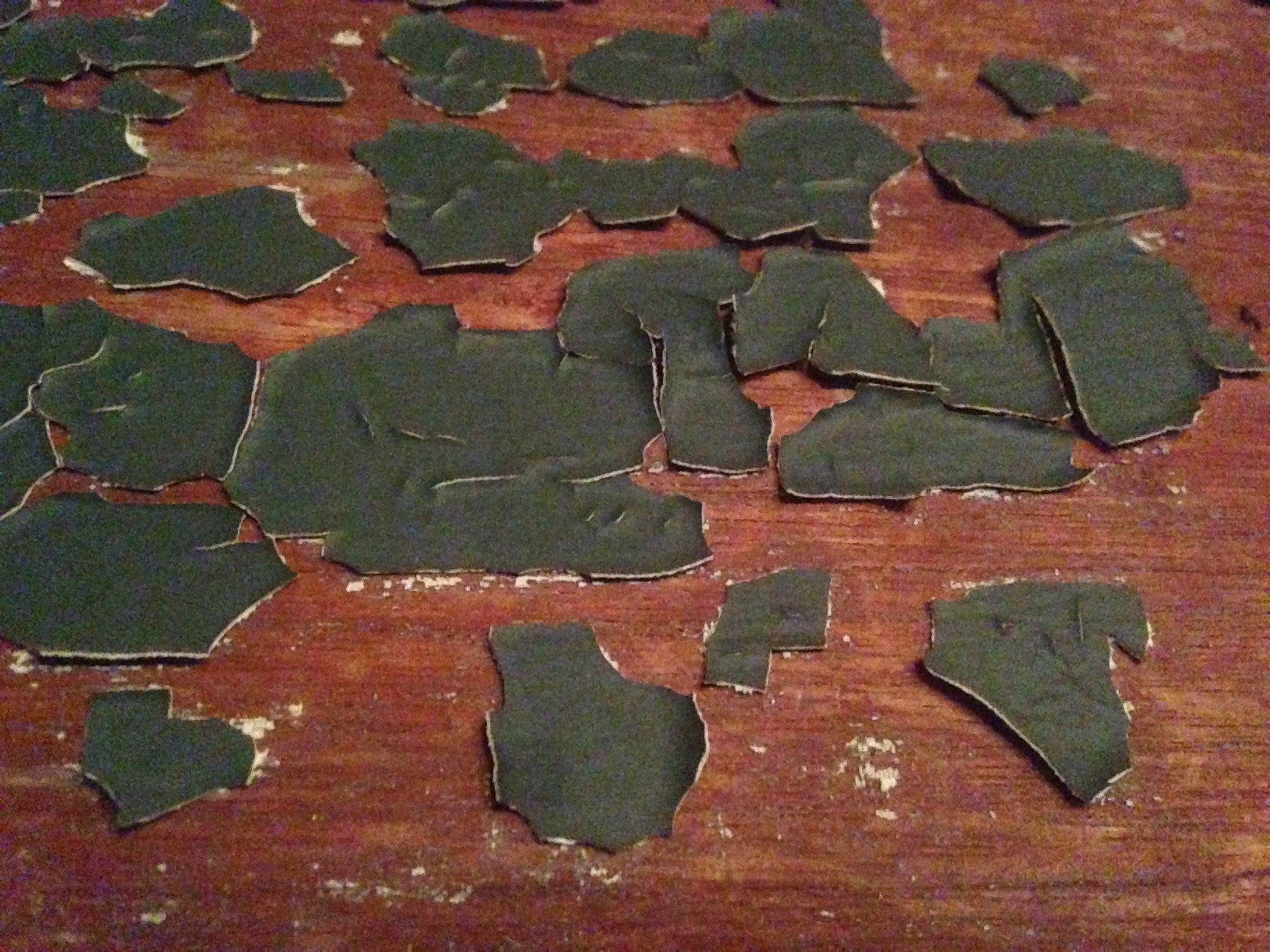 Green old lead paint peeling and cracking off of wood beam or board in barn needs painting